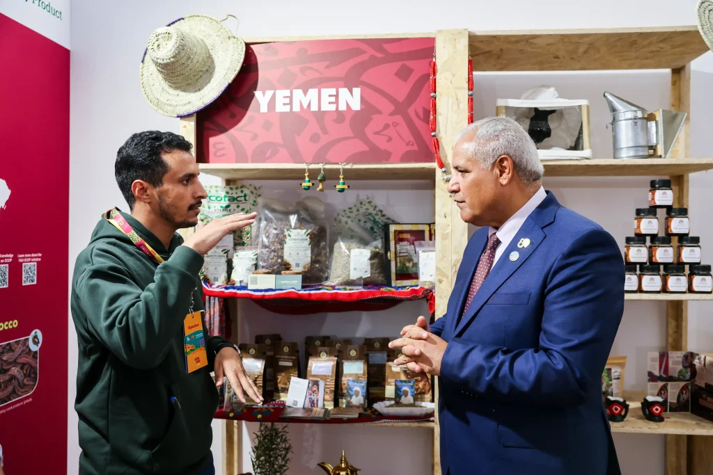 Abdulrazzaq Al-Khishani discussing Yemeni coffee with Abdulhakim Elwaer at the Yemen pavilion during the FAO Global Exhibition 2026 in Rome.